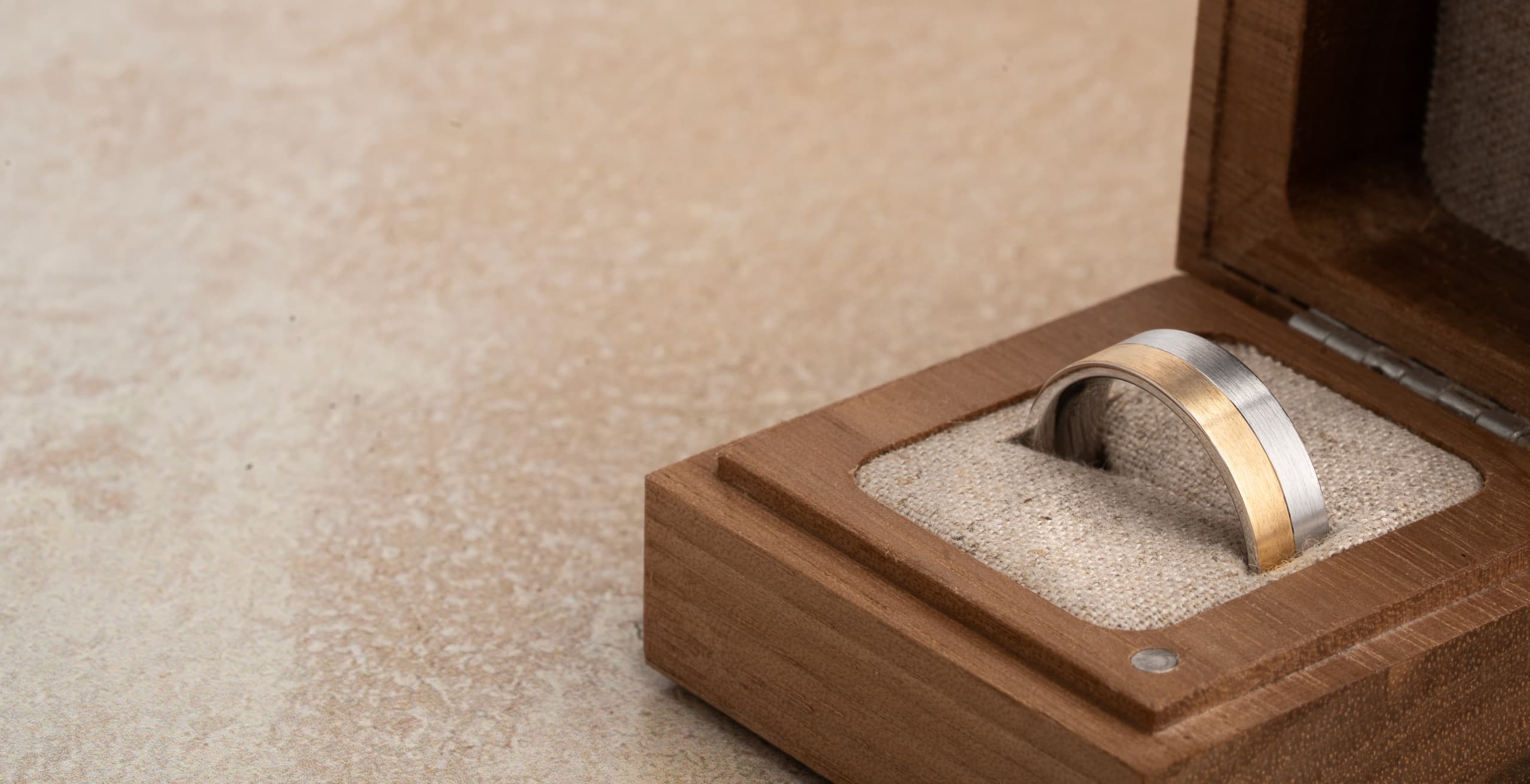 A men's platinum and yellow gold wedding band in a wooden ring box